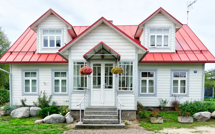 Casa blanca con techo rojo y jardín