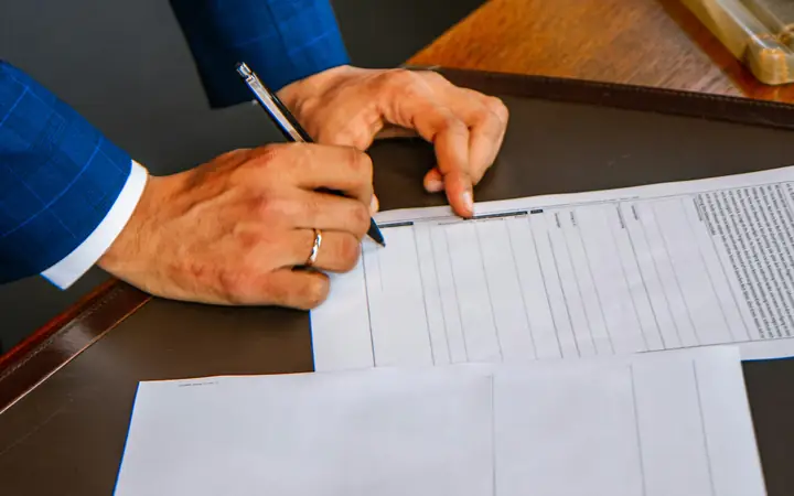 Persona firmando un formulario sobre un escritorio