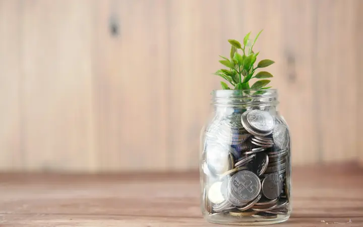 Frasco con monedas y una planta sobre una mesa