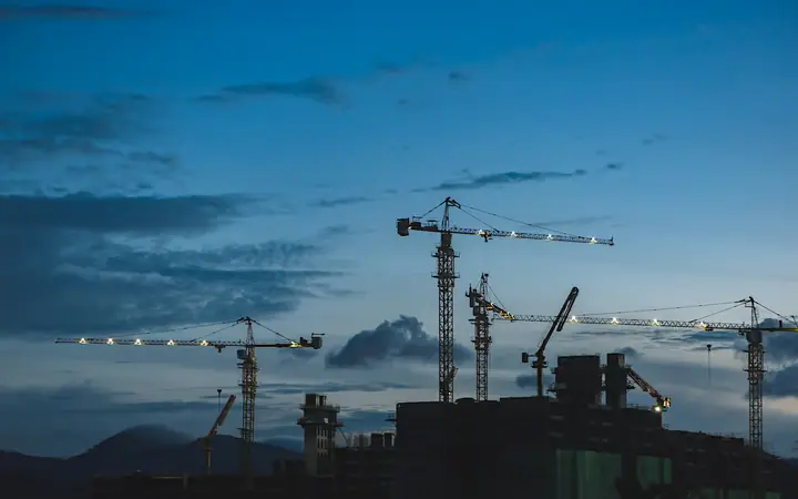 Grúas de construcción recortadas contra el cielo al atardecer