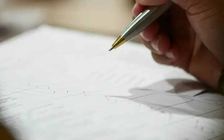 Mano escribiendo con un lápiz sobre una hoja