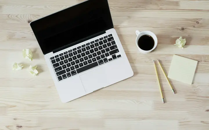 Computador portátil sobre un escritorio de madera con una taza de café